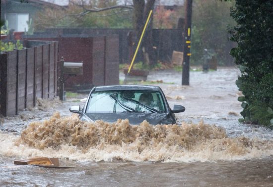 A car evacuates Paso Hondo Road as the Carmel River flood waters rise in Carmel Valley. (David Royal — Monterey Herald Correspondent)